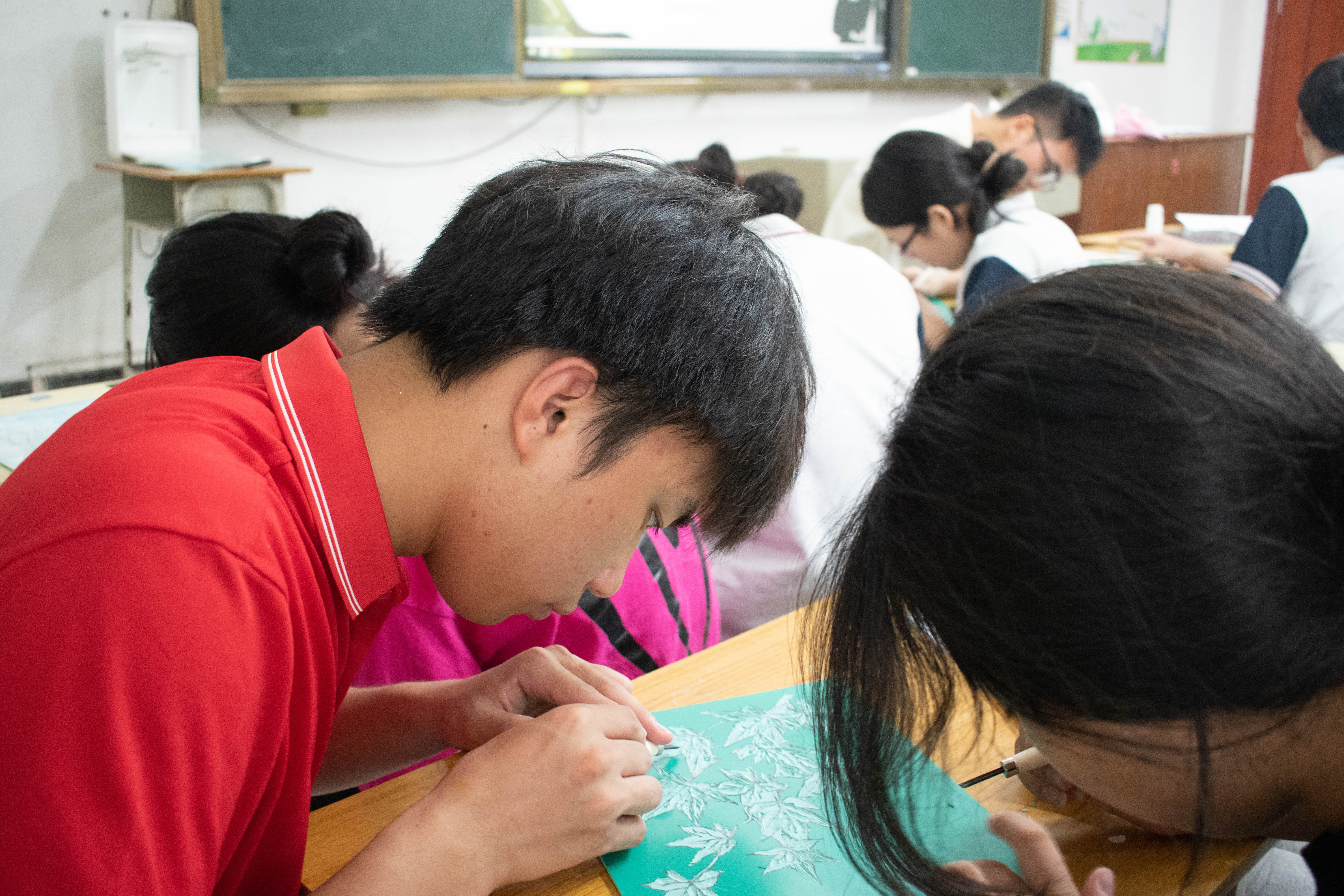 图为融媒体资助宣传实践队队员在棉洋中学教学生版刻现场。(屈泊名 供图)